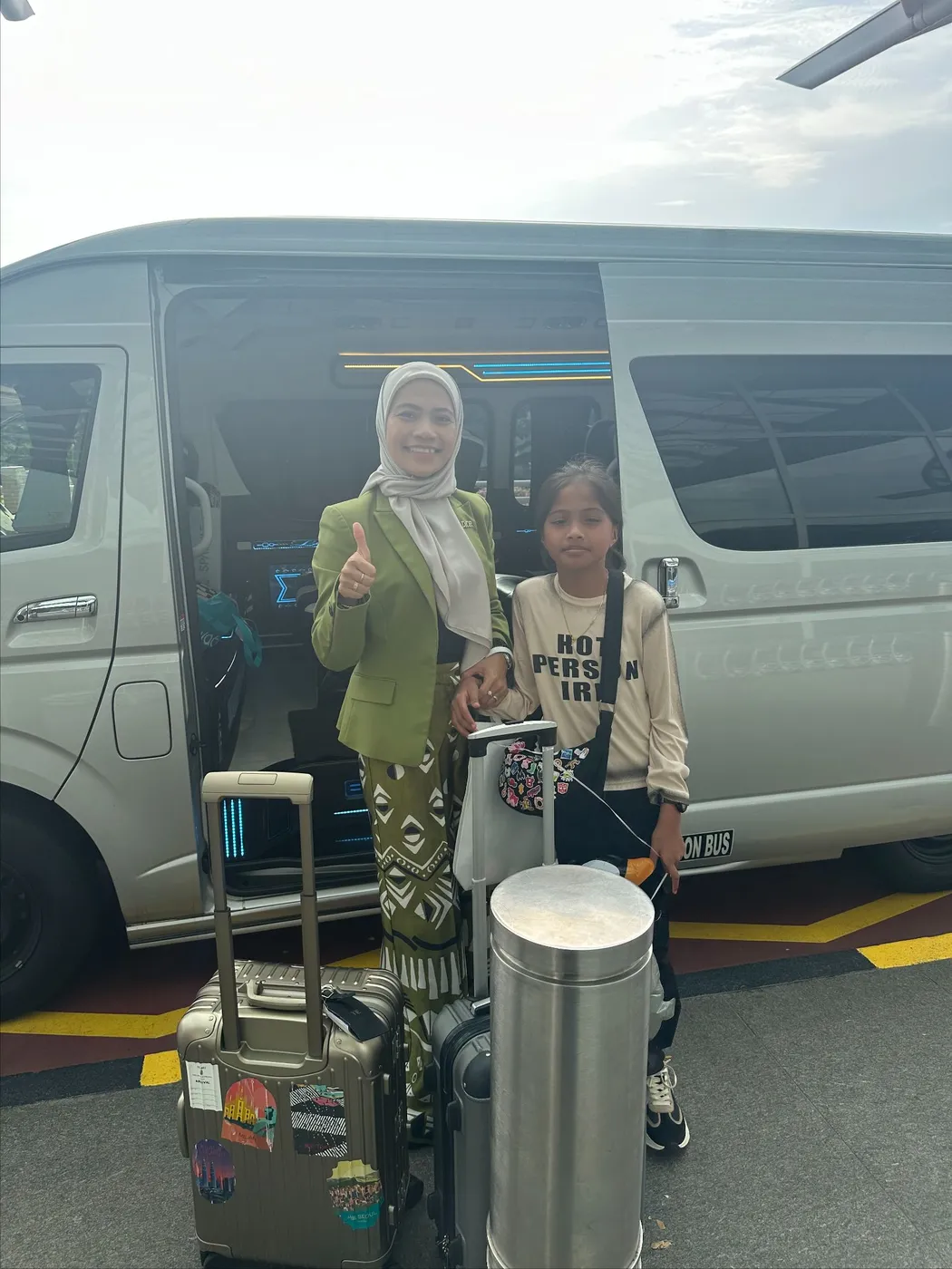 A passenger with her luggage beside the van at the airport