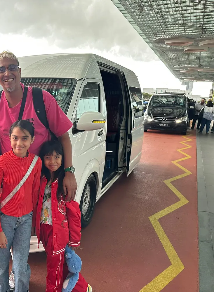 A father and two daughters beside the van at the airport
