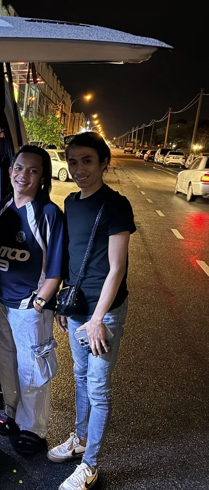 Two passengers beside the van on a night arrival